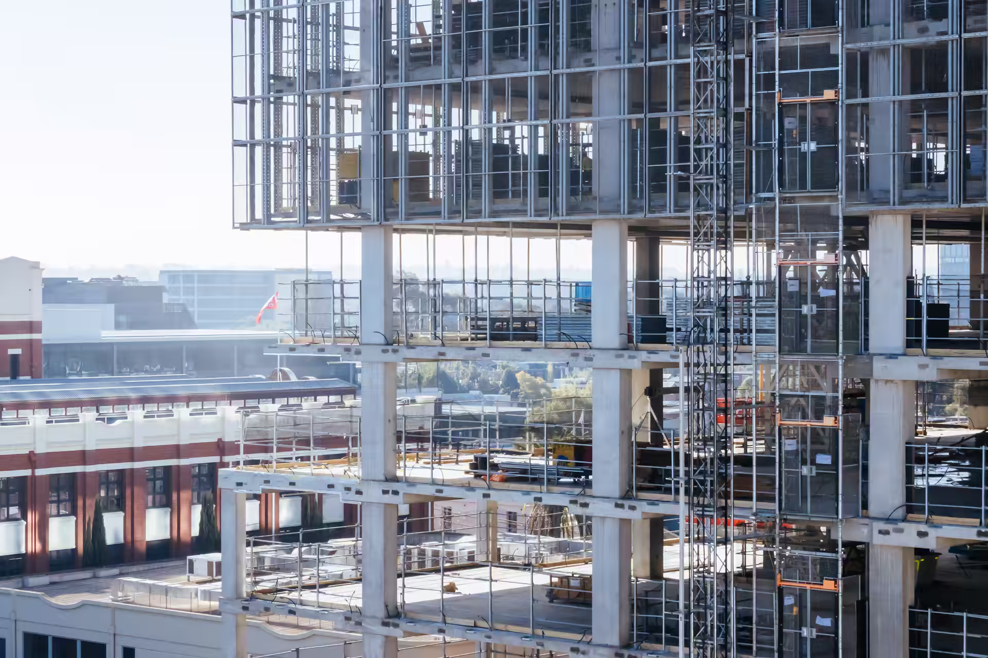 Concrete frame and scaffolding of a multi-storey building under construction beside older brick buildings in Melbourne