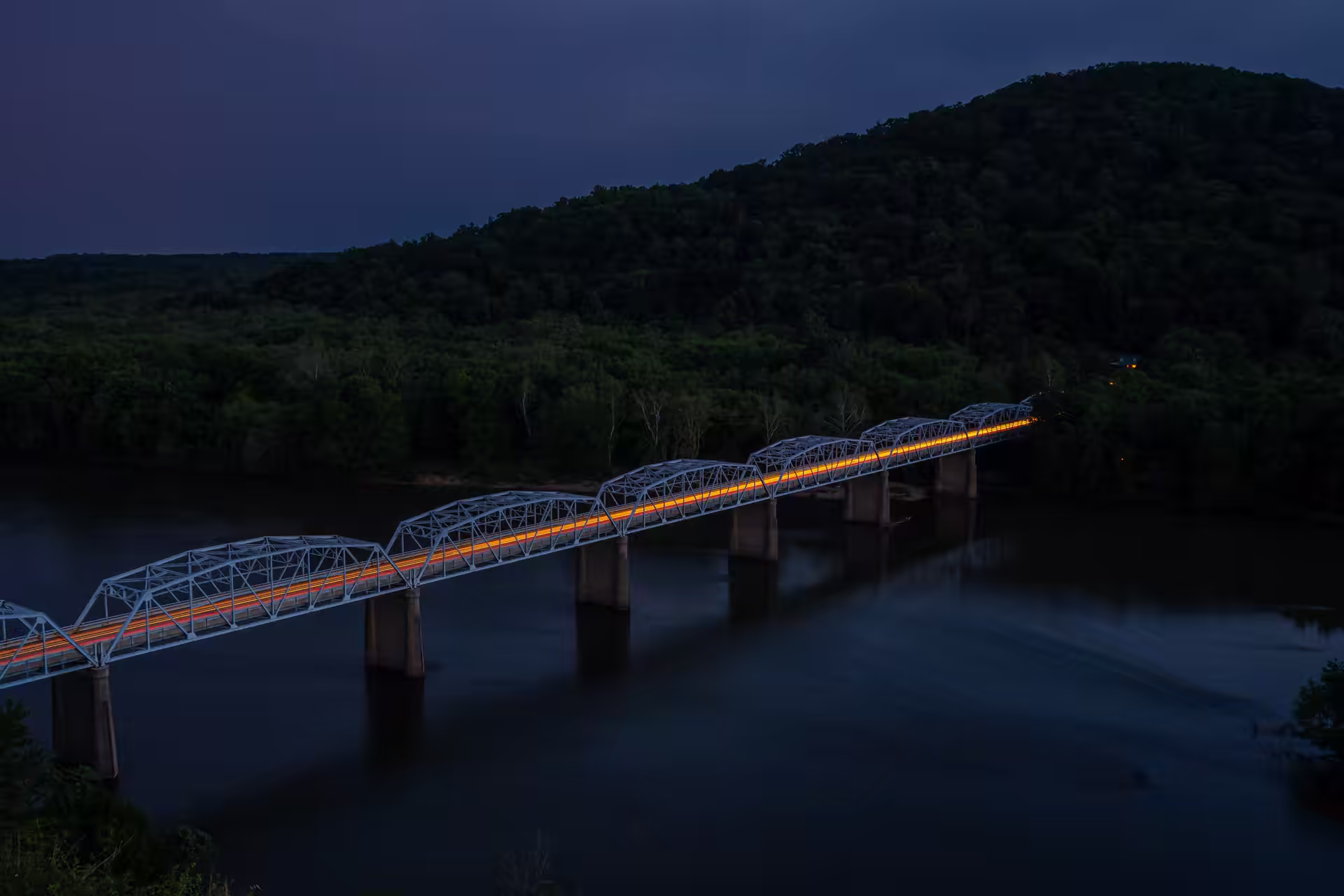 Bridge silhouetted over still water in early morning light