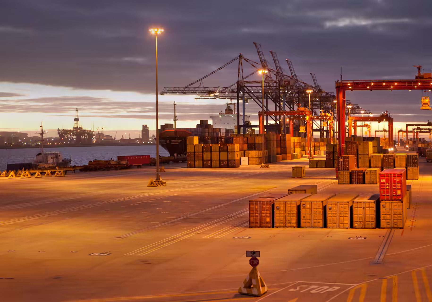 Container cranes standing over a shipping terminal at dawn