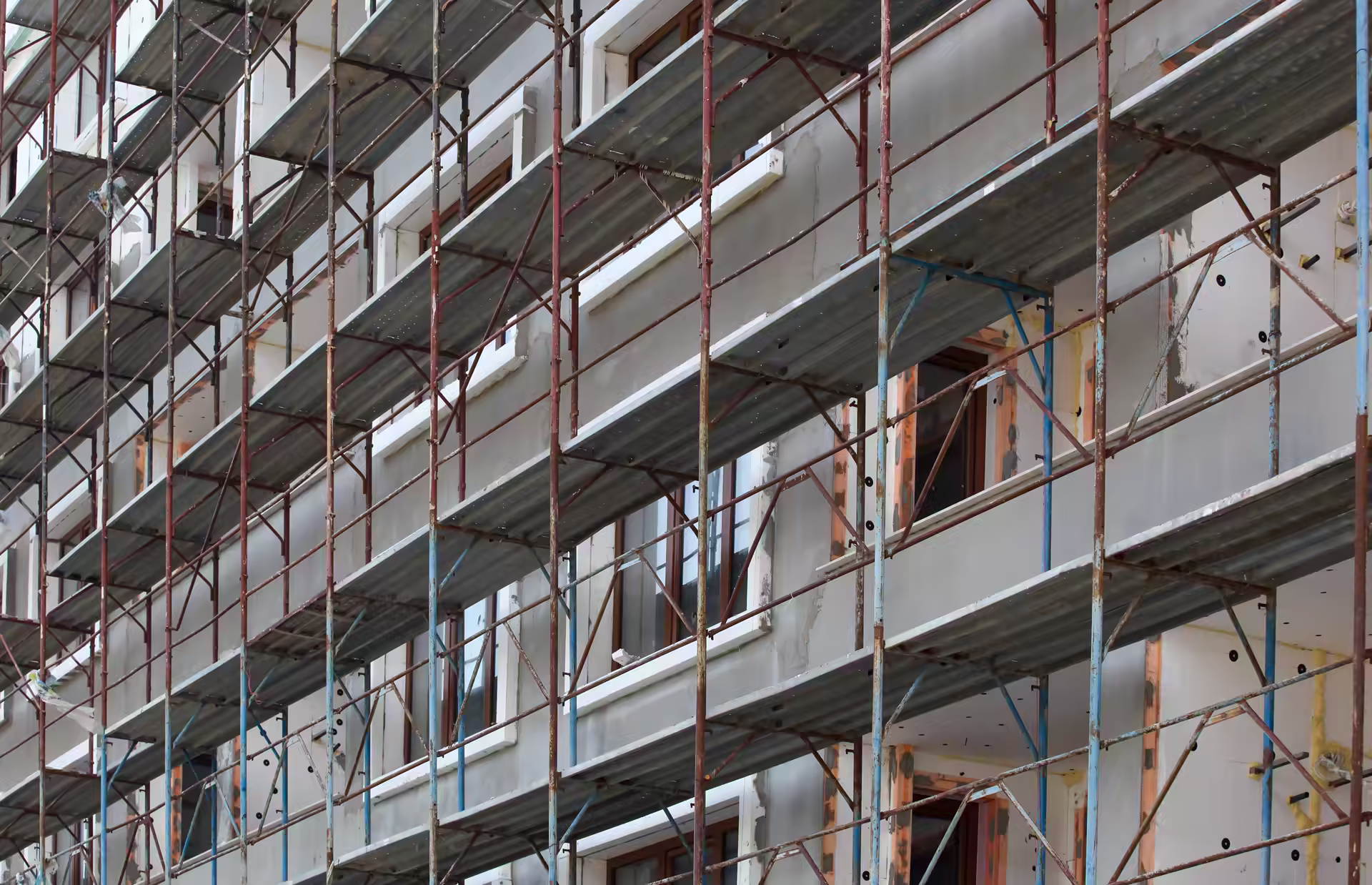 Scaffolding along the grey rendered facade of a building under construction